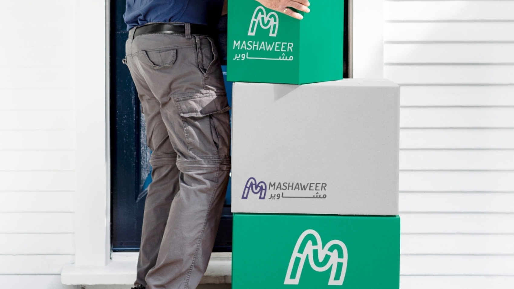 delivery man carriying delivery posts with mashaweer logo on it.